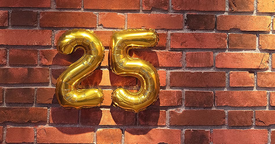 Dos globos como el número 25 frente a una pared de ladrillos
