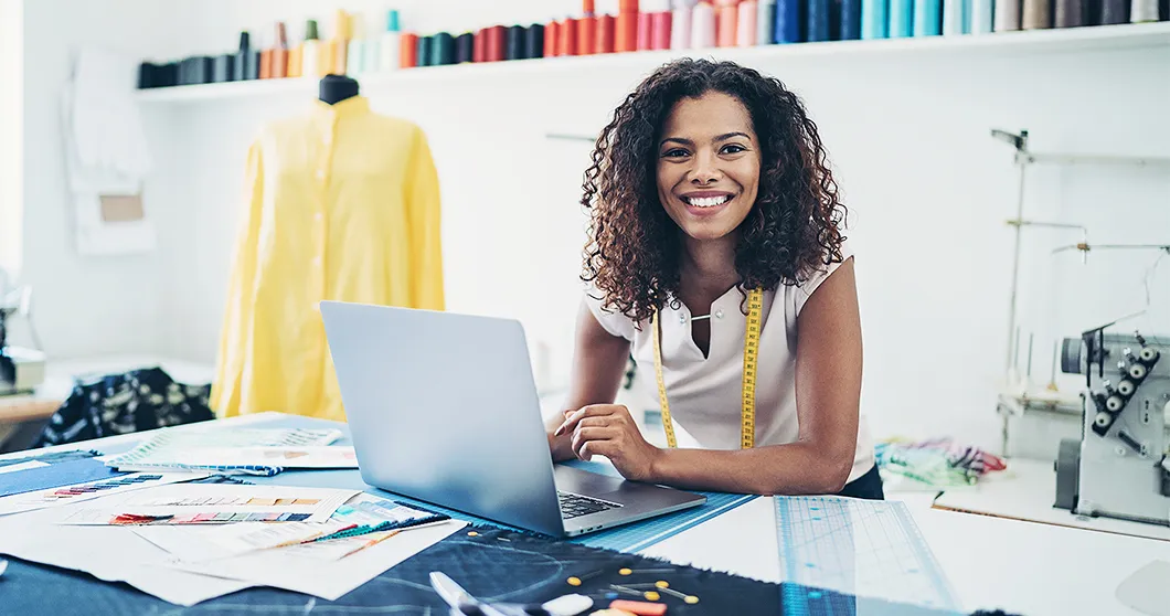 Diseñador de moda en estudio con laptop.